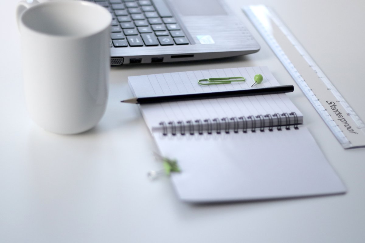 A laptop and notebook arranged on a desk for online study